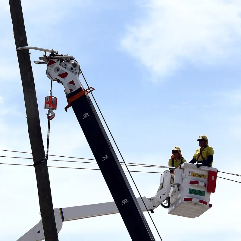 Level 2 electricians in an elevated work platform replacing a timber private power pole